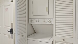 A laundry room with a front-loading washer and dryer, a door with a lock, and a window with blinds. - Sandestin Beachside II Oasis (Miramar Beach)