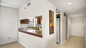 A modern kitchen with a granite countertop, wooden cabinets, and a stainless steel refrigerator. - Sandestin Beachside II Oasis (Miramar Beach)