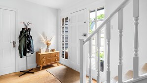 A hallway with a coat rack, wooden dresser, and a staircase. - Stunning 3-Bed House in Saffron Walden (Saffron Walden)