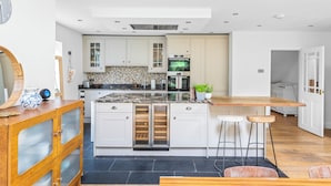 A modern kitchen with white cabinets, a marble countertop, and a built-in oven. - Stunning 3-Bed House in Saffron Walden (Saffron Walden)