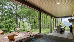 A hot tub with a view of a forest and mountains.