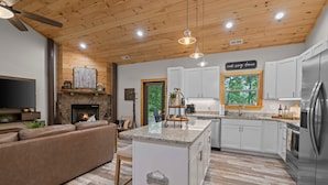 A modern kitchen with white cabinets, a central island, and a built-in oven.