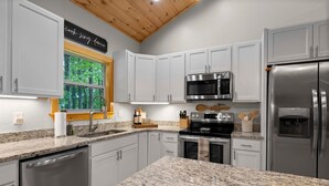 A modern kitchen with granite countertops, stainless steel appliances, and white cabinetry.