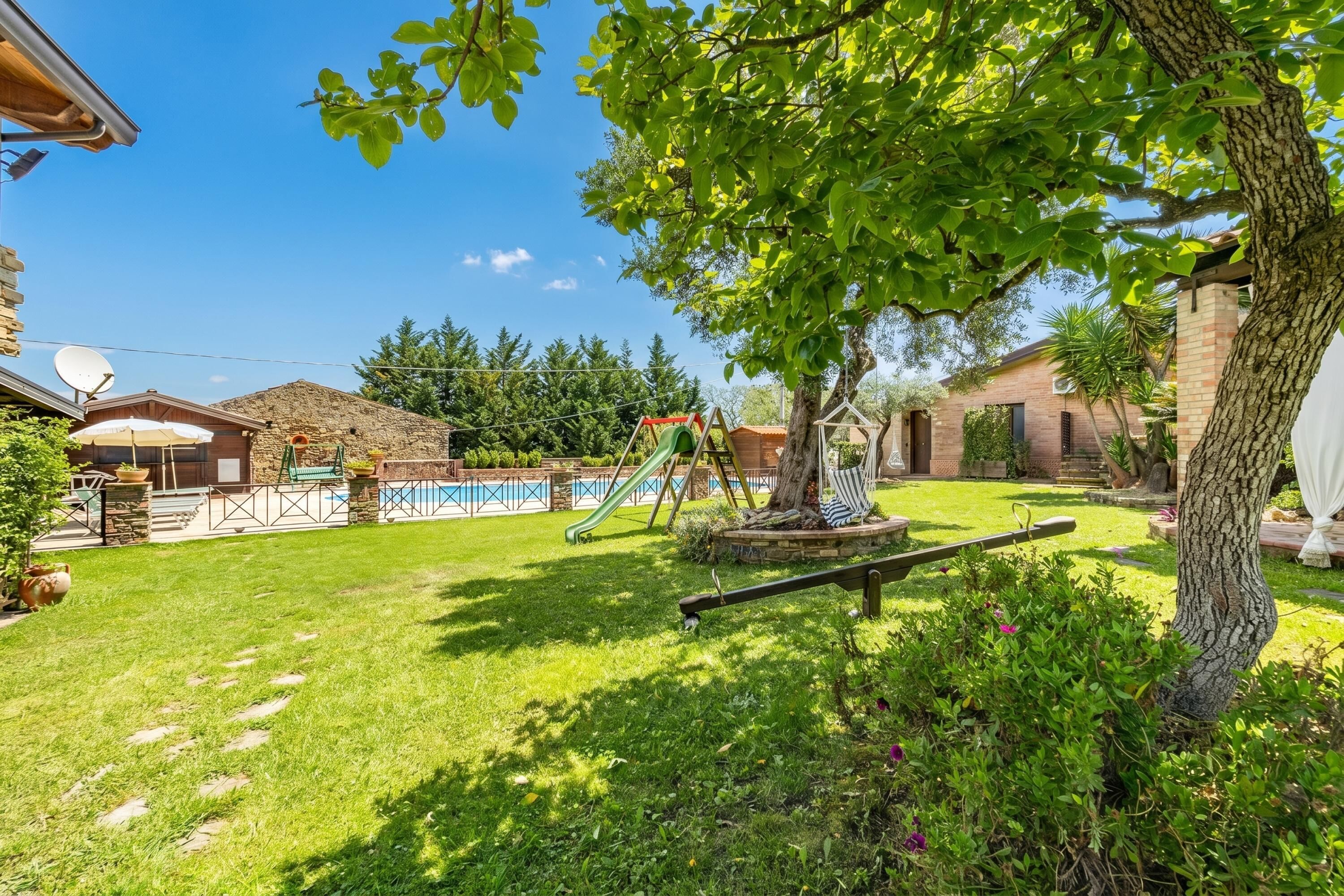 Ein Garten mit Schaukel, Baum und Schwimmbecken.