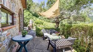 A patio with a table and chairs, a hanging shade, and a view of the surrounding greenery. - Local Stone Cottage With Shared Pool, Casal Velino, Italy (Casal Velino)