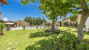 A backyard with a swimming pool, a swing set, and a tree. - Local Stone Cottage With Shared Pool, Casal Velino, Italy (Casal Velino)
