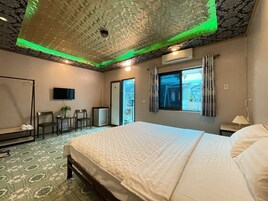 Una habitación de hotel con una cama grande, un escritorio con una silla, un televisor y una ventana con cortinas.