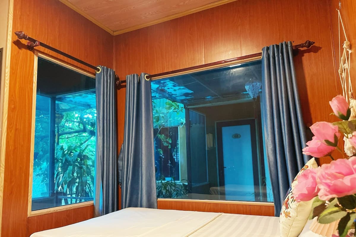 Una habitación con cama, paredes de madera, una ventana con cortinas y vistas al exterior.