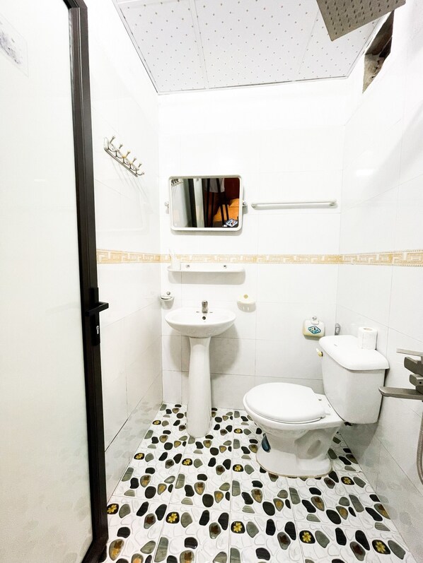 A bathroom with a white sink, toilet, and mirror. The floor has a patterned tile design.