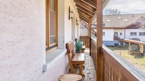 Un balcón con mobiliario de madera, una planta en maceta y vistas a casas vecinas.