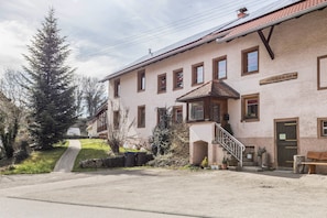 A building with a staircase leading to a porch, a sign above the door, and a bench outside.