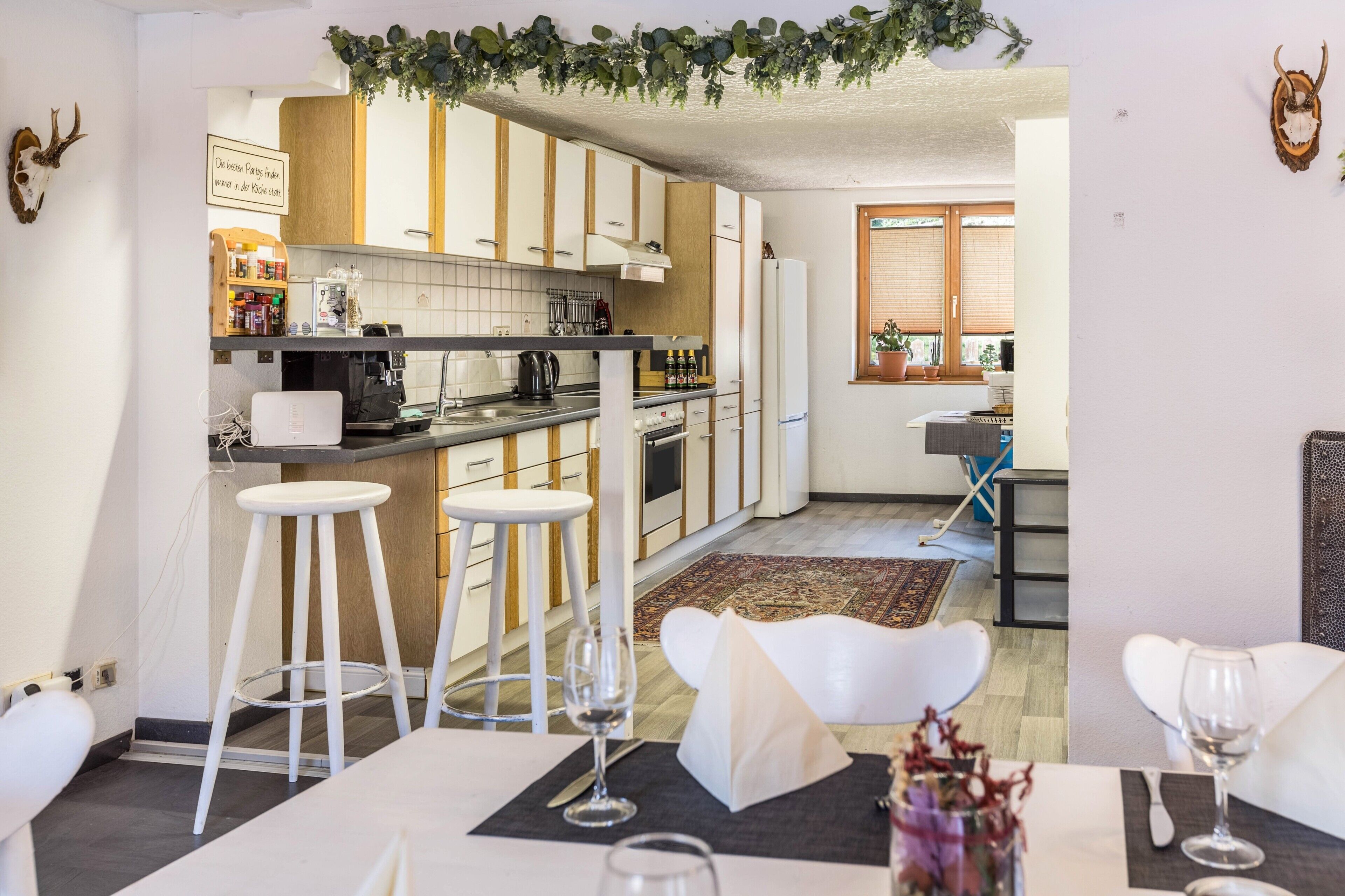 A modern kitchen with white cabinets, a dining area with white chairs, and a bar area.