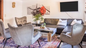 Una sala de estar moderna con un sofá, sillones, una mesa de centro y un televisor de pantalla plana.