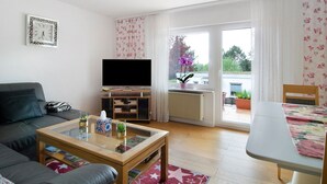 Een woonkamer met een bank, salontafel, televisie en uitzicht op het groen.