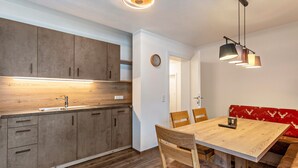 A modern kitchen with wooden cabinets, a built-in sink, and a dining area with a wooden table and chairs.