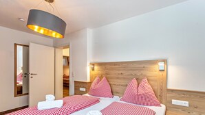 A hotel room with two beds, checkered bedding, a wooden headboard, a mirror, and a hanging light fixture.