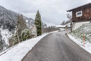 A snow-covered road leading to a wooden building with a picture on the wall. - Holiday flat 'Chalet Berger' with mountain view, communal garden and WiFi. (St. Johann im Pongau)