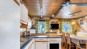 Una cocina compacta con estufa, lavamanos y comedor con sillas y mesa.
