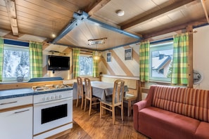 A cozy cabin interior with a kitchen, dining area, and a red sofa. - Holiday flat 'Chalet Berger' with mountain view, communal garden and WiFi. (St. Johann im Pongau)