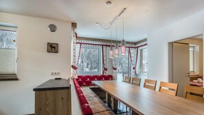 Un comedor con una mesa de madera larga, bancos y una ventana con cortinas.