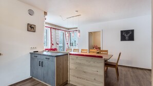 Una cocina moderna con una isla de madera, un área de comedor con mesa y sillas de madera, y un cuadro de un ciervo montado en la pared.