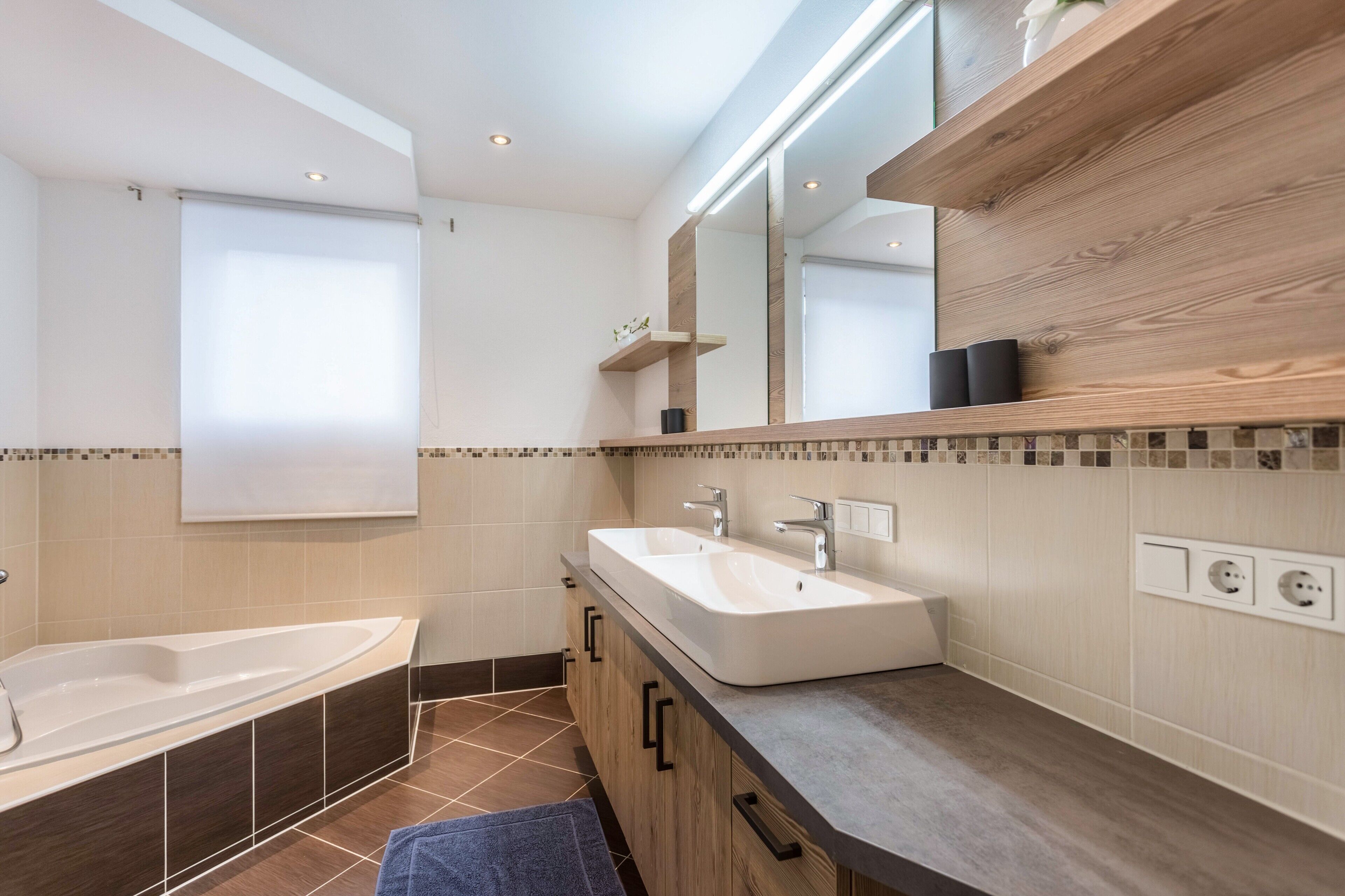 Un baño moderno con una bañera independiente, un tocador doble y un espejo grande.