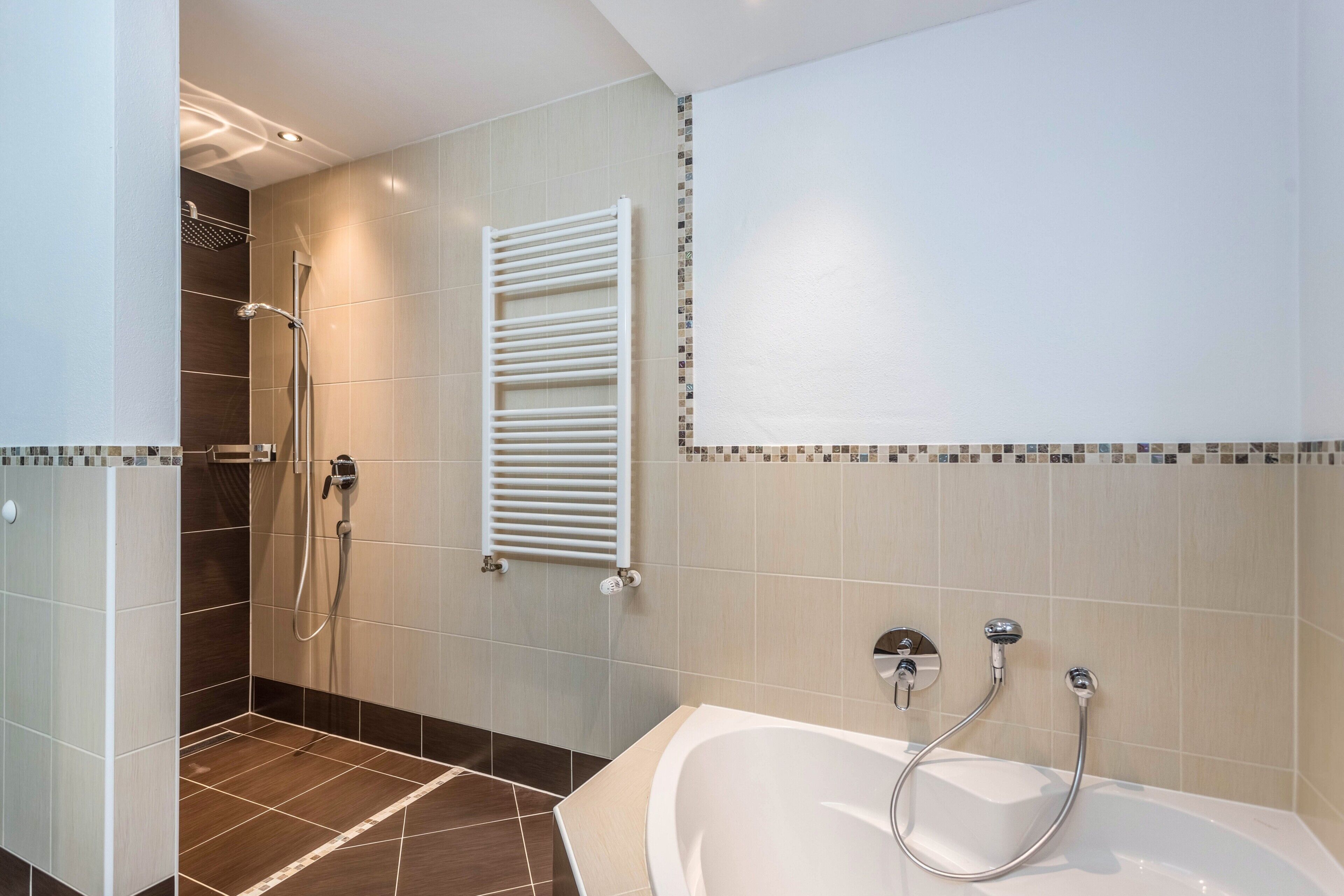 Un baño moderno con ducha, bañera y perchero para toallas.