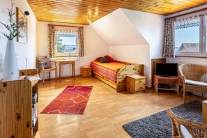Ein gemütliches Zimmer mit Bett, Schreibtisch, Fernseher und Blick nach außen.