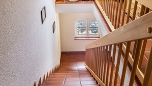 Een trap met houten leuningen en een betegelde vloer die leidt naar een overloop op de tweede verdieping.