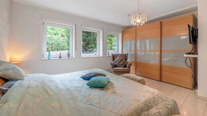 Un dormitorio con cama, una silla, un televisor y un armario.