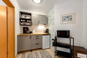 Cocina compacta con armarios grises, microondas y cafetera.