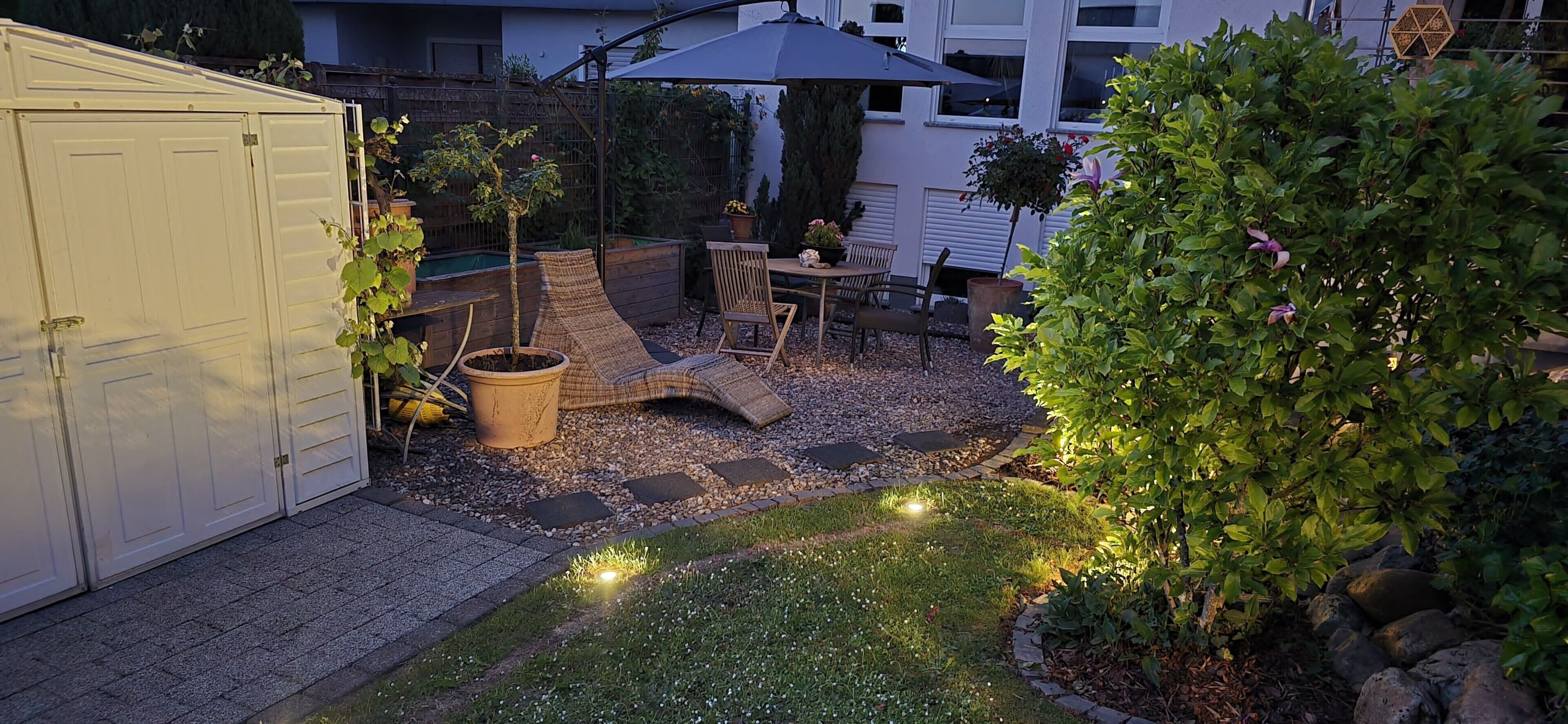 A backyard with a covered patio, a small garden area, and a shed.