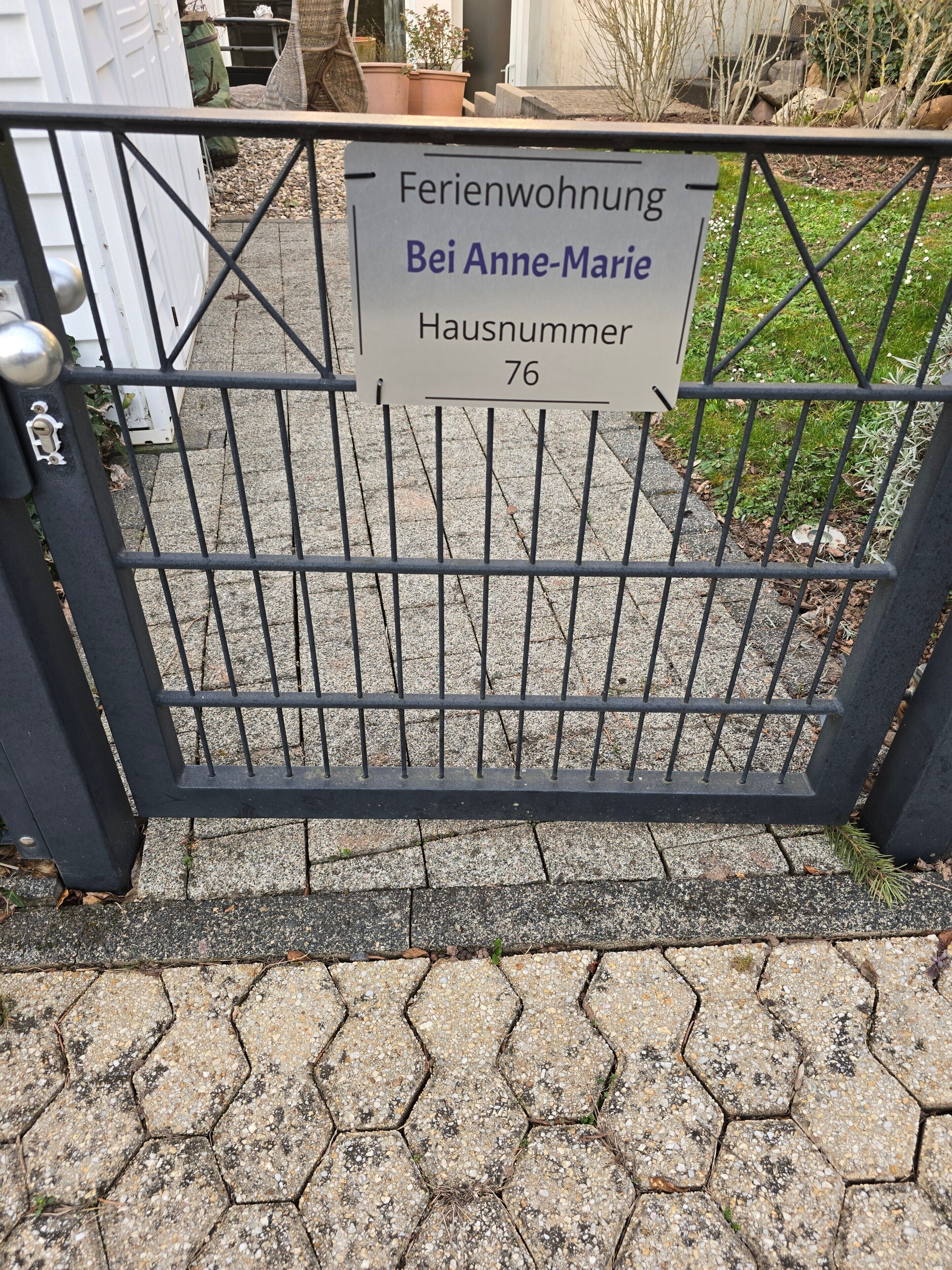 A metal gate with a sign indicating a residential property named 'Bei Anne-Marie Hausnummer 76'.