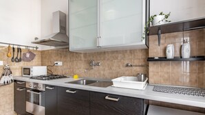 Una cocina moderna con armarios oscuros, un lavamanos de acero inoxidable, un microondas y una estufa a gas.