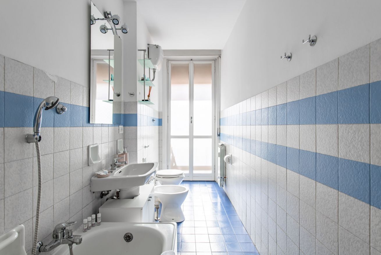 A bathroom with a shower, two sinks, a toilet, and a mirror.