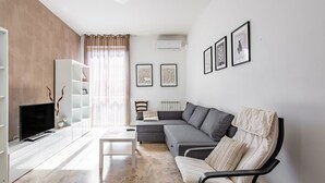 Una sala de estar moderna con sofá, sillón, televisor y estanterías.
