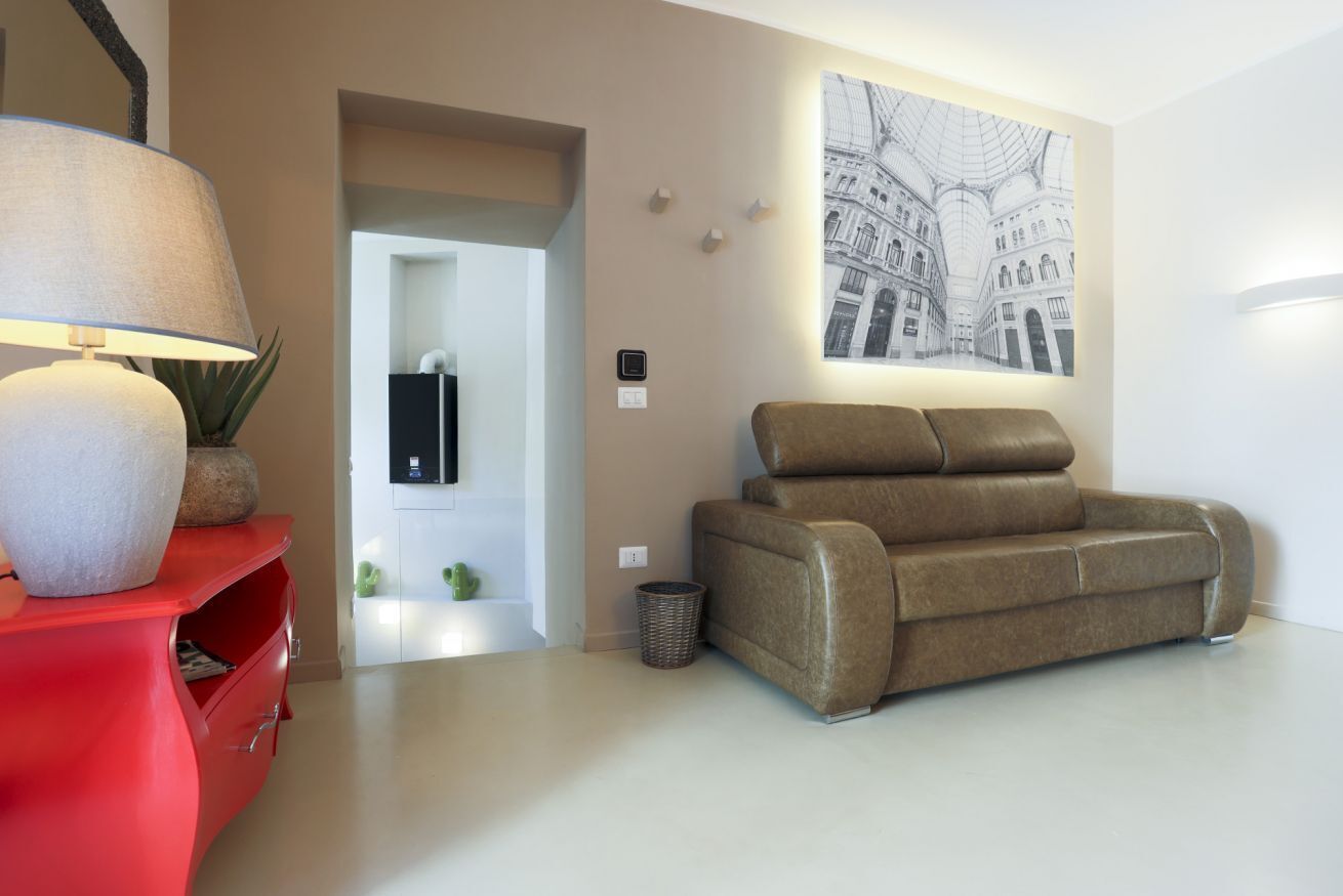 Un soggiorno moderno con un divano, un armadietto rosso, una lampada e un'opera d'arte appesa al muro.