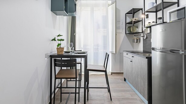 Eine kleine Küche mit Esstisch, Stühlen, einem Backofen und einem Kühlschrank.