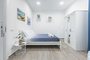 Ein Schlafzimmer mit einem Bett, einem Kleiderschrank, einem kleinen Nachttisch mit Pflanze und Regalen an der Wand.