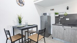 A compact kitchen with a refrigerator, microwave, and a 'Home' sign on the wall.