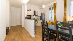 A modern kitchen with white cabinets, a black range hood, and a wooden dining table with chairs. - GuestHost - Borgo Po Comfortable Apartment x4 (Torino)