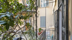 A narrow outdoor corridor with a metal railing, a bicycle, and potted plants. - GuestHost - Borgo Po Comfortable Apartment x4 (Torino)