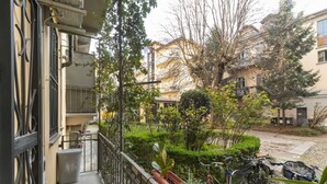 A balcony with a view of a residential area, potted plants, and bicycles. - GuestHost - Borgo Po Comfortable Apartment x4 (Torino)