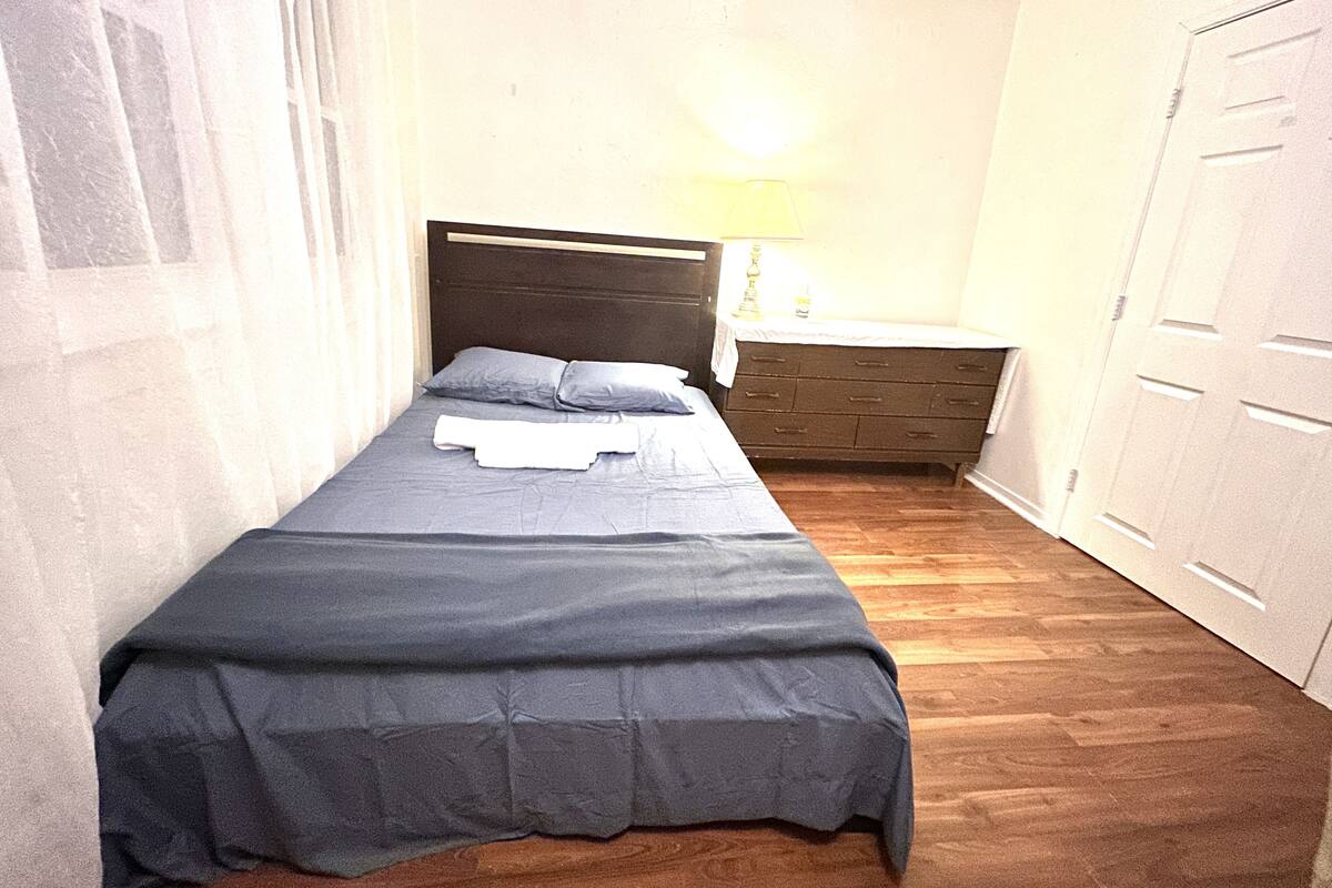 Une chambre à coucher avec un lit, une table de chevet, une lampe et une armoire.