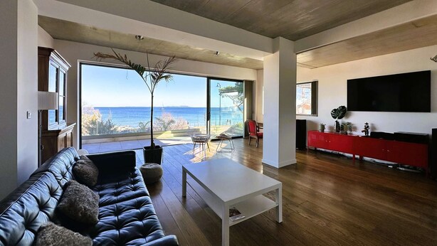 A modern living room with a leather sofa, a white coffee table, and a red entertainment unit. - Air-conditioned villa for 7 people with sea view, rooftop, and beach access in Hyères (HYERES)