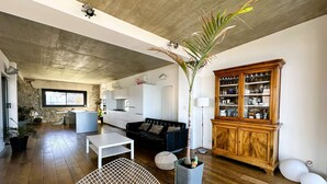 A modern living room with a concrete ceiling, a wooden cabinet with glass doors, and a large plant. - Air-conditioned villa for 7 people with sea view, rooftop, and beach access in Hyères (HYERES)