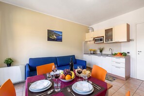 Un espacio habitable compacto con zona de comedor, kitchenette y sofá.