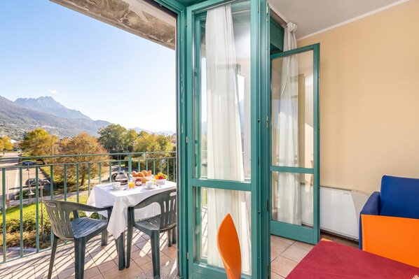 A balcony with a table set for breakfast, a chair, and a sofa.