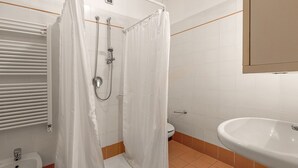 Une salle de bain avec douche, toilettes et lavabo.