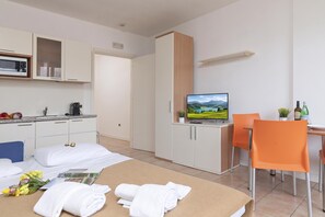 A hotel room with a bed, a desk with a computer, a television, and a kitchenette. - Porto Letizia P19, Porlezza, Italy (Porlezza)